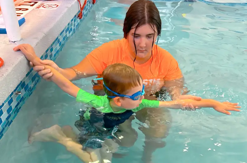 Girl kid learning to swim with women coach at swimming pool